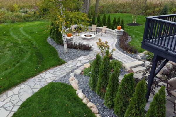 Backyard landscaping with brick over patio and cobblestone walkway