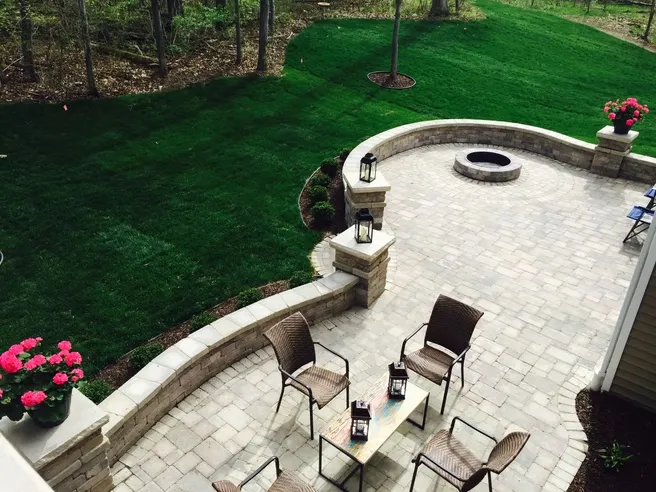Brick Paver Walkway leading to a spacious backyard patio with a fire pit, seating area, retaining wall, and landscaped lawn.